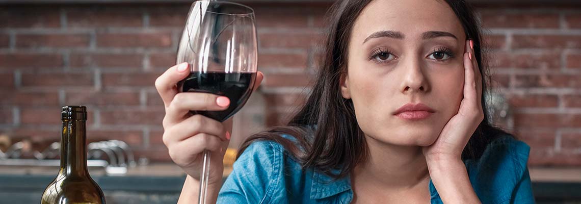 грустная женщина с бокалом вина смотрит в камеру